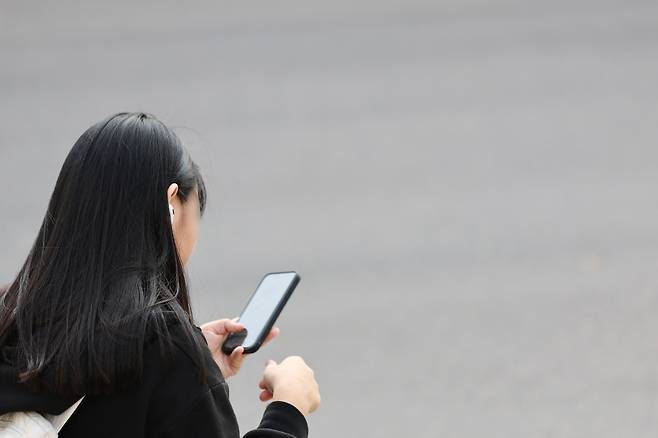 A middle school student is seen using her phone on her way home from school at a street in central Seoul on Nov. 4, 2024. [YONHAP]