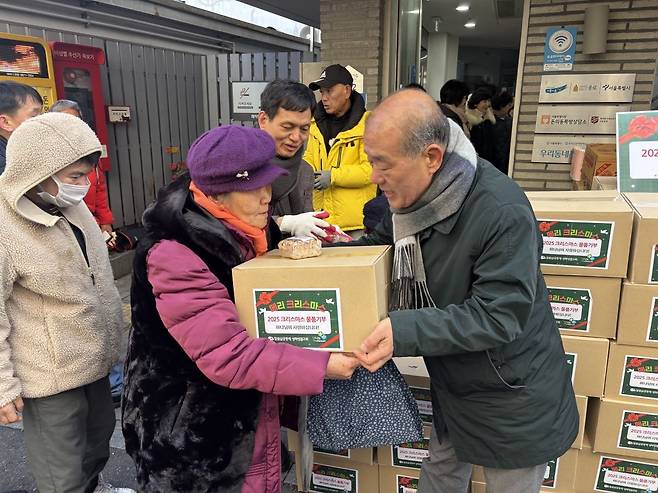 성락교회 교인이 25일 용산구 동자동 쪽방촌을 방문해 주민에게 선물 상자를 전달하고 있다. 교회 제공