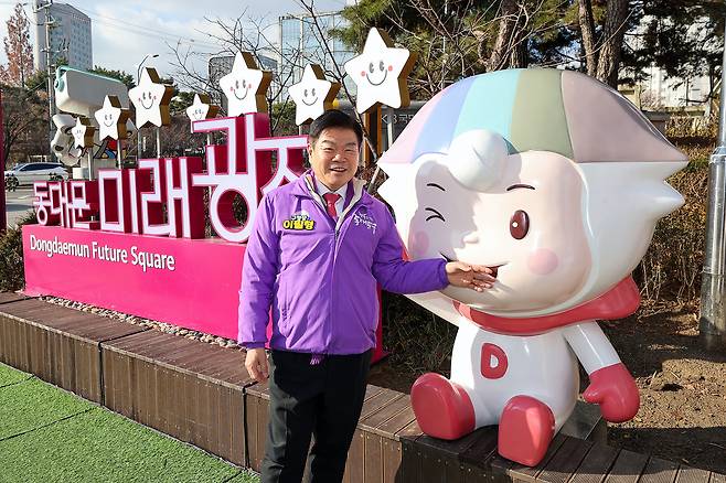 이필형 동대문구청장이 동대문 미래광장이라고 적힌 조형물 옆에서 디디미 캐릭터 조형물에 손을 올리고 있는 사진이다.