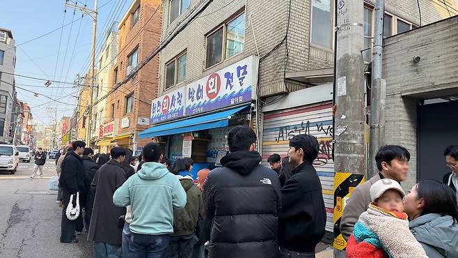 A crowd of people lined up outside a restaurant known for its yellowtail sashimi in Mapo District, western Seoul, on Dec. 17. [WOO JI-WON]