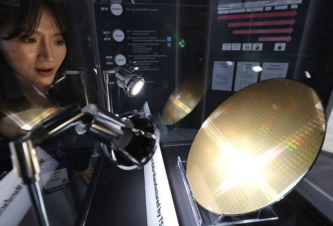 2023년 10월 25일 서울 강남구 코엑스에서 열린 반도체대전(SEDEX)의 한 부스에서 관계자가 반도체 웨이퍼를 살펴보고 있다. 연합뉴스