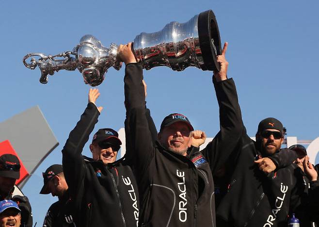 래리 엘리슨 오라클 최고경영자(CEO)가 지난 2013년 9월 25일 미국 캘리포니아주 샌프란시스코에서 열린 제34회 아메리카스컵 요트 대회에서 에미레이트 팀 뉴질랜드를 꺾고 종합 우승을 차지한 오라클 팀 USA 선수들과 함께 트로피를 들어 올리고 있다.  (사진=로이터)