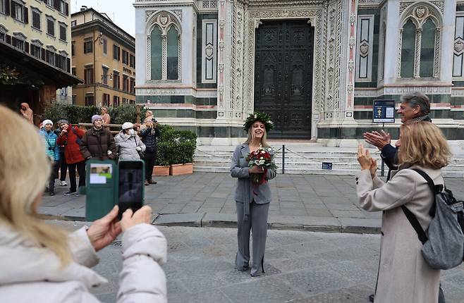 월계관을 쓴 대학 졸업생이 2025년 12월11일 이탈리아 피렌체의 피렌체대성당 앞에서 가족과 친지들의 축하를 받고 있다.