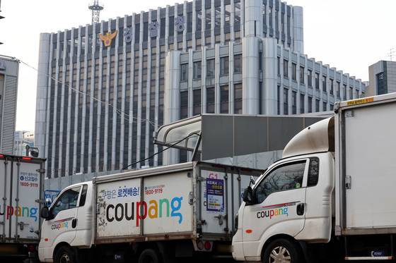 28일 서울 시내 한 쿠팡 물류센터 앞에 주차돼 있는 쿠팡카(쿠팡 배송트럭) 너머로 경찰청이 보이고 있다. 뉴스1.