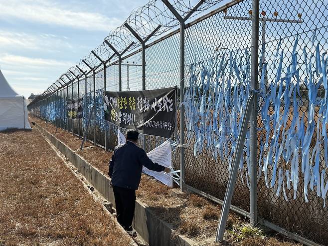 Park In-wook, 69, picks up litter around the fence area close to the runway of Muan International Airport in South Jeolla, where an airplane carrying his families crashed last year, on Dec. 22. [LEE SOO-JUNG]