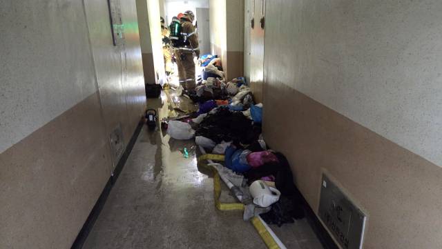 29일 오전 울산 남구 달동의 한 아파트 화재 현장 복도에서 소방대원들이 잔불 정리 등 후속 조치를 하고 있다. 복도 바닥에는 화재 진압에 사용된 물이 흥건하게 고여 있고, 불이 난 세대 내부에서 꺼낸 것으로 보이는 각종 쓰레기와 집기류가 어지럽게 널려 있어 당시 긴박했던 상황과 진화 작업의 어려움을 짐작하게 한다. 울산소방본부 제공