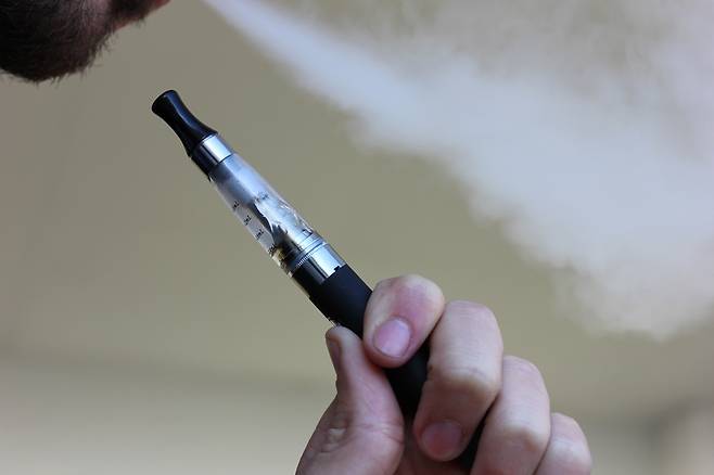 A person smokes an e-cigarette in this file photo. [JOONGANG ILBO]