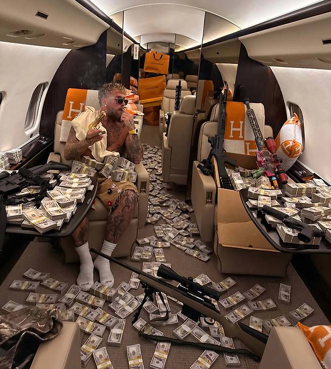 제이크 폴이 전용기 안에 돈 다발을 뿌려 과시하고 있다. [제이크 폴 인스타그램 갈무리]