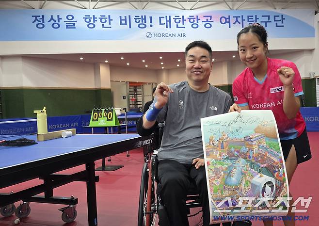 파리패럴림픽 남자복식 은메달리스트 박성주(횐쪽)과 파리올림픽 동메달리스트 신유빈이 파리패럴림픽 포스터를 들고 파이팅 포즈를 취했다.