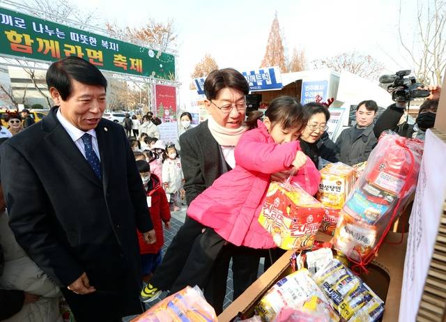 2025년 12월 10일 덕진공원에서 열린 ‘전주와 함께라면 축제’에서 우범기(왼쪽 두 번째) 전주시장이 한 아이를 안고 라면을 기부하고 있다. /전주시