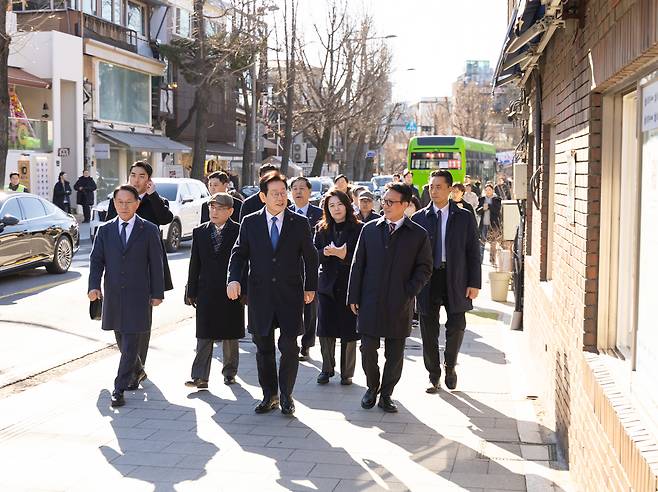 President Lee Jae Myung, center, walks along a street in Samcheong-dong near the Blue House after a Cabinet meeting on Dec. 30, 2025. [PROVIDED BY THE BLUE HOUSE]