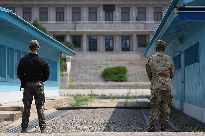 South Korean soldiers stand guard at the Joint Security Area (JSA) in Panmunjom, inside the DMZ, during a tour on July 19, 2022. The JSA, with its iconic blue huts (South Korean side) and the grey Panmun-gak building (North Korean side in the background), is one of the few spots in the DMZ where troops from both Koreas face each other directly under the armistice agreement. [JOONGANG ILBO]