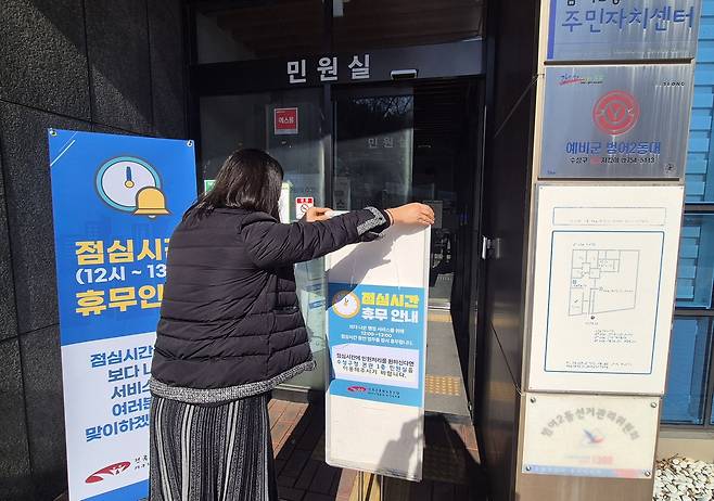 '오늘부터 점심시간 쉽니다'  (대구=연합뉴스) 박세진 기자 = 2일 대구 수성구 범어2동 행정복지센터 직원이 출입문에 점심시간 휴무를 알리는 안내판을 설치하고 있다. 2026.1.2. psjpsj@yna.co.kr