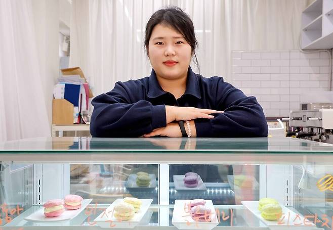 ▲&nbsp;인천 중구 신포동에 위치한 수제 마카롱 가게 '마카롱데이즈'의 박소슬 대표. 대표 메뉴 '다쿠마롱' 모형앞에서 포즈를 취하고 있다. /조연우 인턴기자 bonun@incheonilbo.com