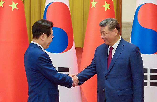 South Korean President Lee Jae Myung (left) and Chinese President Xi Jinping shake hands prior to their summit talks at the Great Hall of the People in Beijing on Monday. (Pool photo via Yonhap)