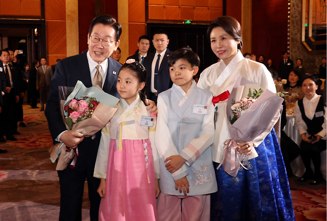 이재명 대통령과 김혜경 여사가 4일 중국 베이징의 한 호텔에서 열린 재중 한국인 간담회에서 화동들에게 환영의 꽃다발을 받고 기념촬영을 하고 있다. [베이징 김호영 기자]