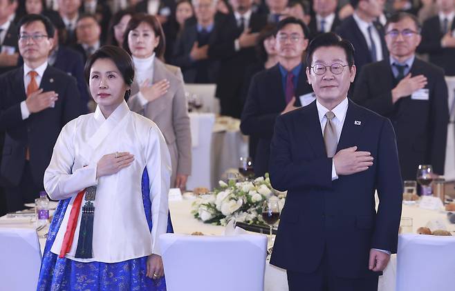 이재명 대통령과 김혜경 여사가 지난 4일 중국 베이징 한 호텔에서 열린 재중 한국인 간담회에서 국기에 경례하고 있다. [연합]