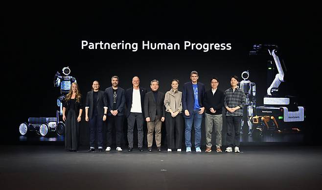 Starting second from left: Carolina Parada, head of robotics at Google DeepMind; Alberto Rodriguez, director of the Atlas behavior division at Boston Dynamics; Boston Dynamics CEO Robert Playter; Hyundai Motor Group Vice Chairman Chang Jae-hoon Chang; Aya Durbin, head of humanoid application strategy at Boston Dynamics; Zachary Jackowski, head of Atlas development at Boston Dynamics; and other key officials pose for a photo at Hyundai Motor Group’s Media Day during CES 2026 in Las Vegas on Monday. (Hyundai Motor Group)