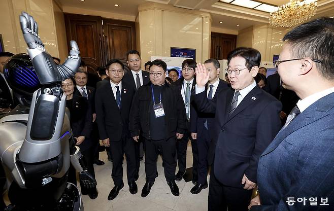 이재명 대통령이 7일 중국 상하이 국제회의중심에서 열린 한중 벤처 스타트업 서밋 행사에서 중국 기업 아지봇의 휴머노이드 로봇과 악수를 하고 있다.  상하이=송은석 기자 silverstone@donga.com