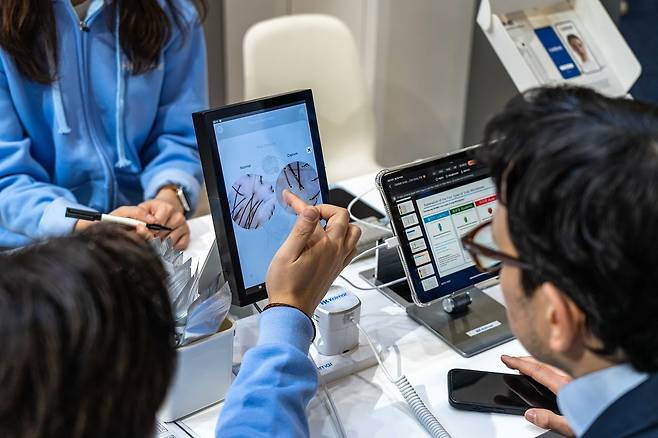 6일(현지시간) 미국 라스베이거스에서 열린 'CES 2026' 한국콜마 부스에 방문한 관람객이 '두피 카이옴(CAIOIME Scalp)'으로 두피 진단 기술을 확인하고 있다. 사진 한국콜마