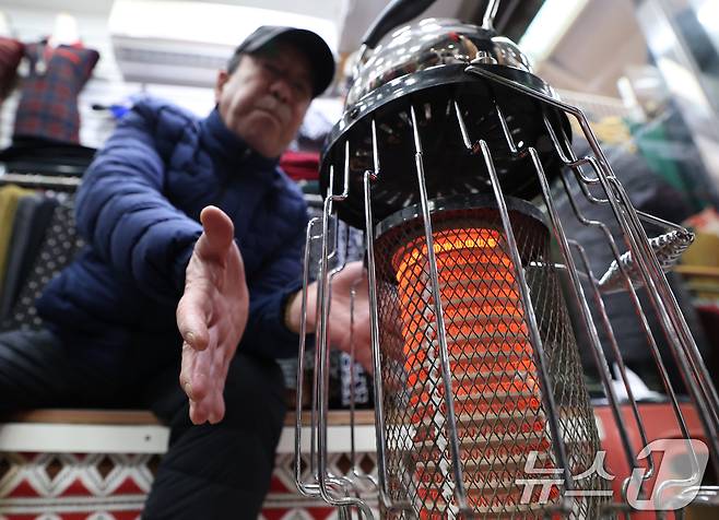 전국 대부분 지역에 영하권 추위를 보인 8일 경기 수원시 팔달구 영동시장에서 상인들이 전기난로에 몸을 녹이고 있다. 2026.1.8/뉴스1 ⓒ News1 김영운 기자