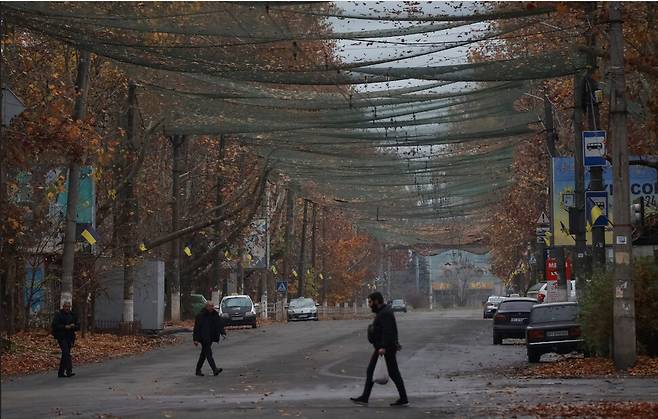 지난해 11월11일 우크라이나 헤르손. 드론 방어 그물로 뒤덮힌 거리를 주민들이 걷고 있다. 로이터 연합뉴스