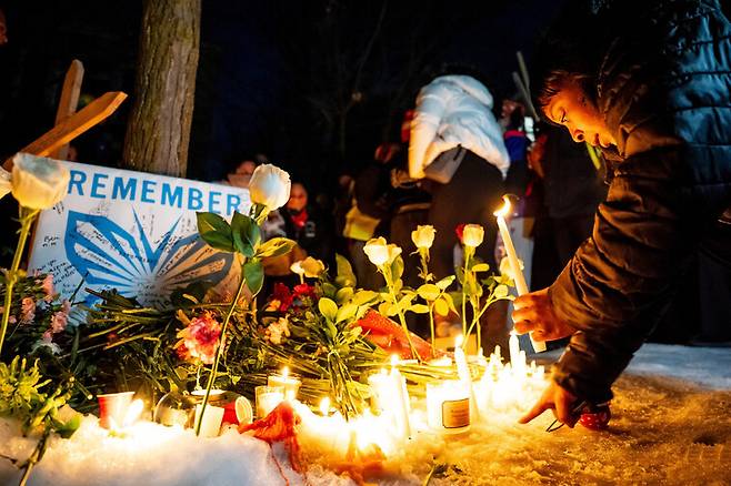 7일 미니애폴리스에서 이민세관국(ICE) 요원이 한 여성을 총격 살해한 장소를 찾은 사람들이 추모의 뜻으로 꽃과 촛불을 놓고 있다. 미니애폴리스/AP연합뉴스