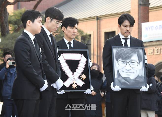 배우 이정재(오른쪽 둘째)와 정우성(맨 오른쪽)이 9일 서울 중구 명동성당에서 진행된 장례미사를 마친 뒤 금관문화훈장과 영정을 들고 대성전을 빠져나오고 있다. 왼쪽부터 故 안성기 차남 안필립, 장남 안다빈, 이정재, 저우성. 2026. 1. 9.  박진업 기자 upandup@sportsseoul.com