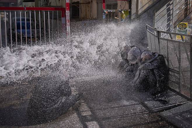 4일(현지시각) 이스라엘 예루살렘에서 경찰이 쏜 물대포가 징병제에 반대하는 시위를 벌이며 거리를 막고 있던 초정통파 유대인 남성들에게 쏟아지고 있다. 예루살렘/AP 연합뉴스