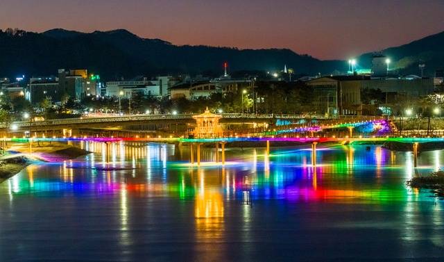 ▲ 한파로 얼어붙은 괴산군 성황천과 동진천 위로 두 하천을 잇는 에코브릿지의 다채로운 색감 경관조명이 빙판에 투영돼 겨울밤 수변의 이색적인 풍경을 연출하고 있다. /괴산군 제공
