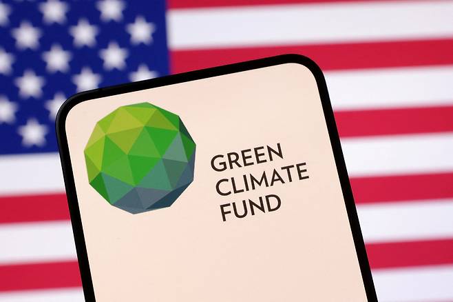 Green Climate Fund logo and the U.S. flag are seen in this illustration taken on April 23, 2025. [REUTERS/YONHAP]