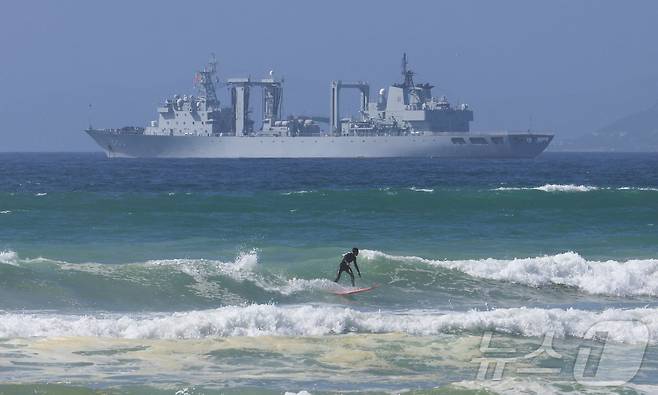 중국, 러시아, 이란 등 '브릭스 플러스' 국가들의 남아프리카해 합동 해상훈련을 앞둔 7일(현지시간) 남아프리카공화국 케이프타운의 사이먼스타운 해군기지 인근 파슬 베이에서 한 서퍼가 중국 선박 앞에서 서핑을 즐기고 있다. 2026.01.07. ⓒ 로이터=뉴스1 ⓒ News1 이정환 기자