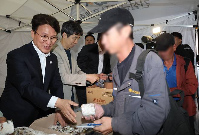 김민석 국무총리가 지난해 10월10일 서울 구로구 남구로 새벽인력시장을 찾아 근로자들에게 떡을 나눠주고 있다. 연합뉴스