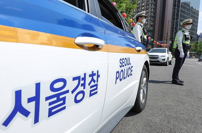 A police patrol car and two police officers are seen in downtown Seoul in 2022. [YONHAP]