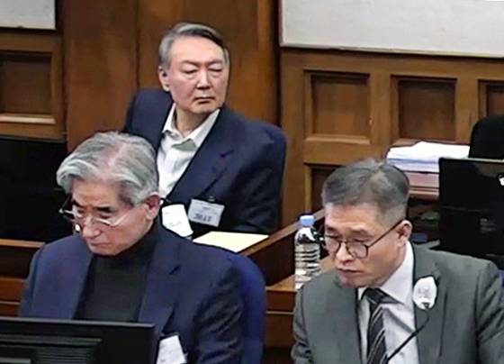 지난 9일 서울중앙지법 417호 법정에서 열린 내란 우두머리 혐의 공판에 출석한 윤석열 전 대통령(뒷줄)과 김용현 전 국방부 장관(앞줄 왼쪽)이 재판을 지켜보고 있다. [서울중앙지방법원 제공 영상 캡처]