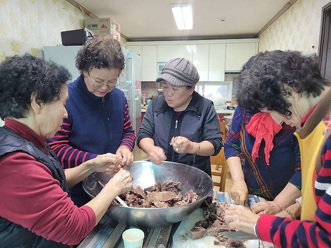 마을 최대 잔치인 대동계를 맞아 마을회관에서 70대 언니들이 삶은 고기를 찢고 있다.
