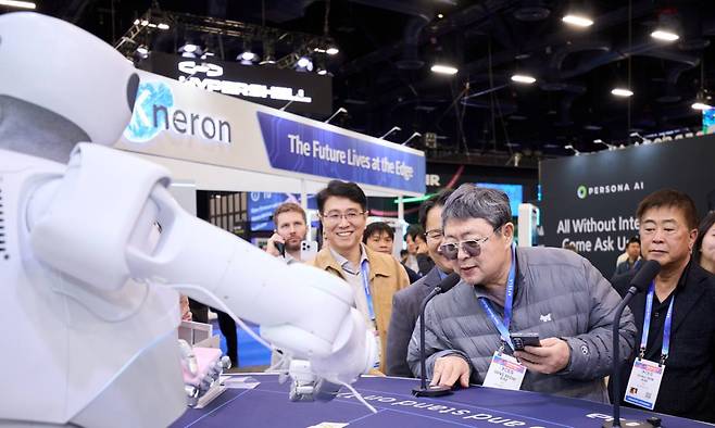 이수그룹 김상범(앞줄 가운데) 회장이 CES 2026에서 피지컬 AI 기업 부스를 둘러보며 로봇과 대화를 나누고 있다.