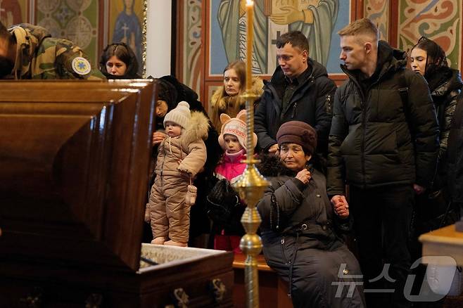 12일(현지시간) 우크라이나 키이우의 성 미하일 황금돔 수도원에서 열린 장례식에서 러시아 공격으로 사망한 의료진 세르기 스몰랴크의 관 앞에서 그의 유족과 지인들이 애도하고 있다. 2026.01.12 ⓒ AFP=뉴스1 ⓒ News1 김지완 기자