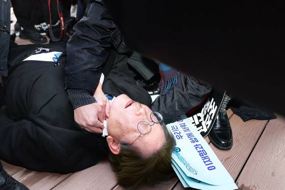 2024년 1월 2일 이재명 당시 더불어민주당 대표가 부산 가덕도 신공항 부지를 둘러본 후 기자들과 문답을 진행하던 중 왼쪽 목 부위에 습격을 당해 피를 흘린 채 쓰러져 있다. 연합뉴스