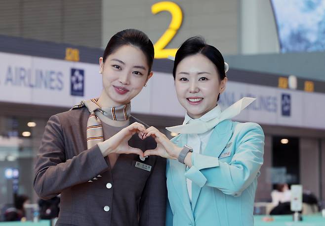 Asiana Airlines and Korean Air staff pose for a photo at Incheon International Airport Terminal 2 on Jan. 14, after Asiana moved its check-in counters and terminals as part of its integration with Korean Air. [JOINT PRESS CORPS]