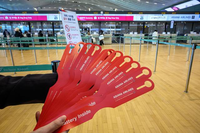아시아나항공이 인천공항 제2여객터미널 운항을 개시한 14일 인천국제공항 2터미널 아시아나항공 체크인 카터에서 한 직원이 ‘노 배터리(NO BATTERY)’ 태그를 나눠주고 있다. 연합뉴스.