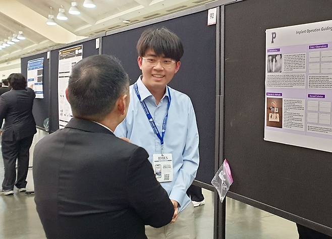 2024년 미국 의생명학회(BMES) 연례 학회에서 현주원 학생이 임플란트 수술 가이드 연구 내용을 담은 포스터 앞에서 기념촬영을 하고 있다. /디에이치랩스 제공