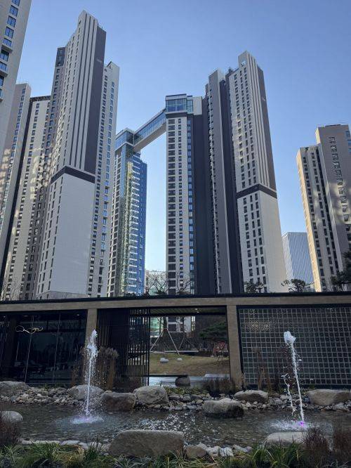 서울 송파구 '잠실 르엘' 단지 전경. 단지 내 수경시설(분수)과 조경이 조성된 가운데 상부에 동을 잇는 스카이브릿지가 보인다. 롯데건설