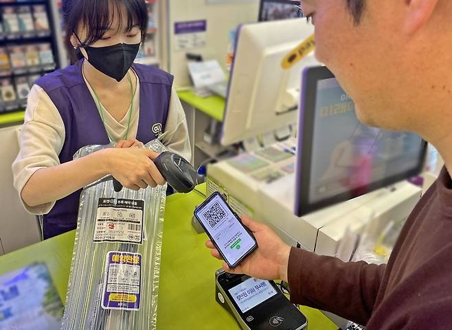 고객이 포켓CU 앱으로 사전 예약한 제품을 받고 있다.  [CU 제공]