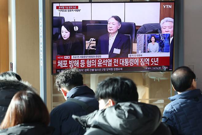 16일 서울역 대합실에서 시민들이 고위공직자범죄수사처(공수처) 체포 방해 등 혐의로 기소된 윤석열 전 대통령에 대한 1심 선고 공판 생중계를 보고 있다.  이날 재판부는 윤 전 대통령에 징역 5년을 선고했다.  연합뉴스