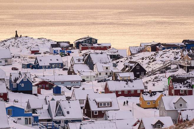 [누크=AP/뉴시스] 14일(현지 시간) 그린란드 누크에서 주민들이 눈 쌓인 거리를 걸어가고 있다. 2026.01.15.