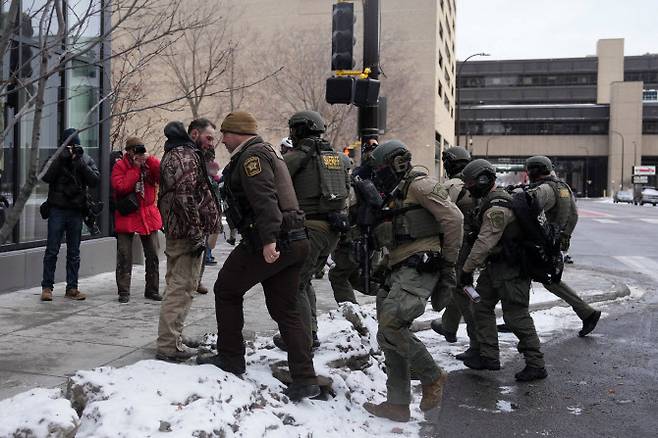 17일(현지시간) 미국 미네소타주 미니애폴리스에서 우익 활동가가 주도한 반이슬람 시위가 끝난 뒤, 한 무리에게 쫓기던 인물이 법집행관들이 다가오는 가운데 서 있다. (사진=로이터)