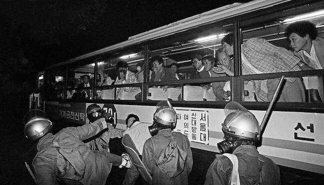 1990년 10월13일 시민∙학생∙노동자 등 20여만 명이 참석한 가운데 서울 보라매공원에서 열린 ‘보안사 불법사찰 규탄과 군정청산 국민대회’를 마치고 시위를 벌이던 대학생들을 전경들이 집단구타하자 버스 승객들이 애처로운 눈으로 바라보고 있다.