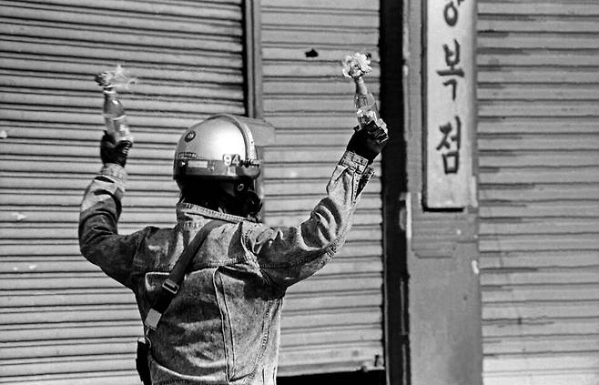 1990년 5월1일 서울지역총학생회연합 소속 대학생들이 서울 동대문 근처 도로를 점거한 채 현대중공업과 한국방송공사 공권력 투입과 관련해 시위를 벌이던 중 한 백골단원이 학생들이 던진 화염병을 들어 다시 학생들에게 던지려 하고 있다.