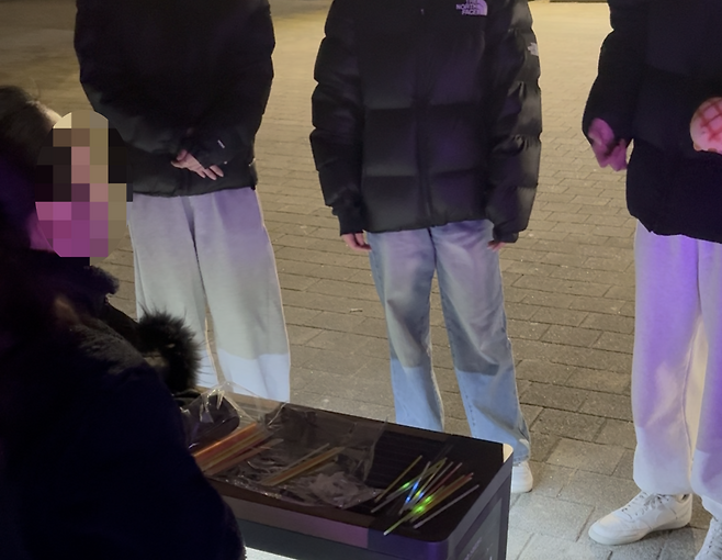 Park Hyo-beom (left) passes out glow sticks on Saturday, at Ttukseom Hangang Park, to participants before starting the first round of Cops and Robbers. (The Korea Herald/Lee Seung-ku)